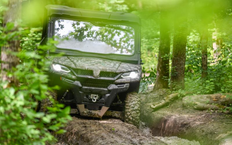 UTV driving on dirt trail in wooded area