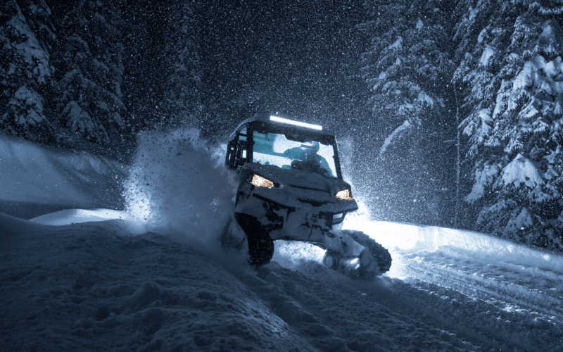 UTV with lights on driving through snow in winter at night